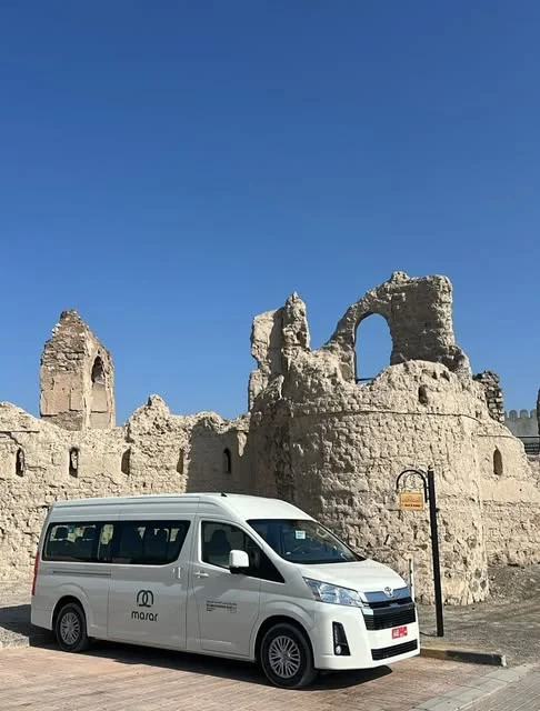 حافلة صغيرة أمام مبنى تراثي حجري